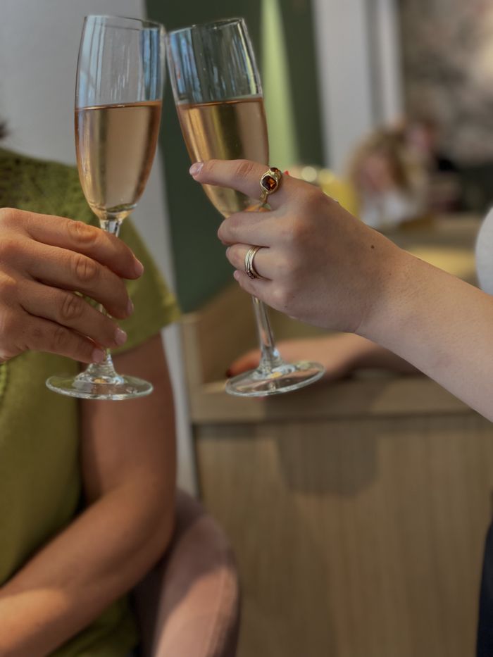 Zwei Gäste stoßen mit einem Glas Sekt an