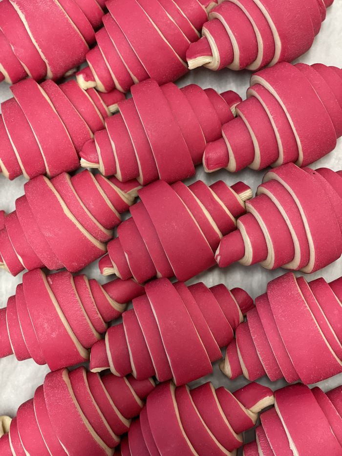 Ungebackene Croissants aus rosa und weiß geschichtetem Teig, dicht nebeneinander